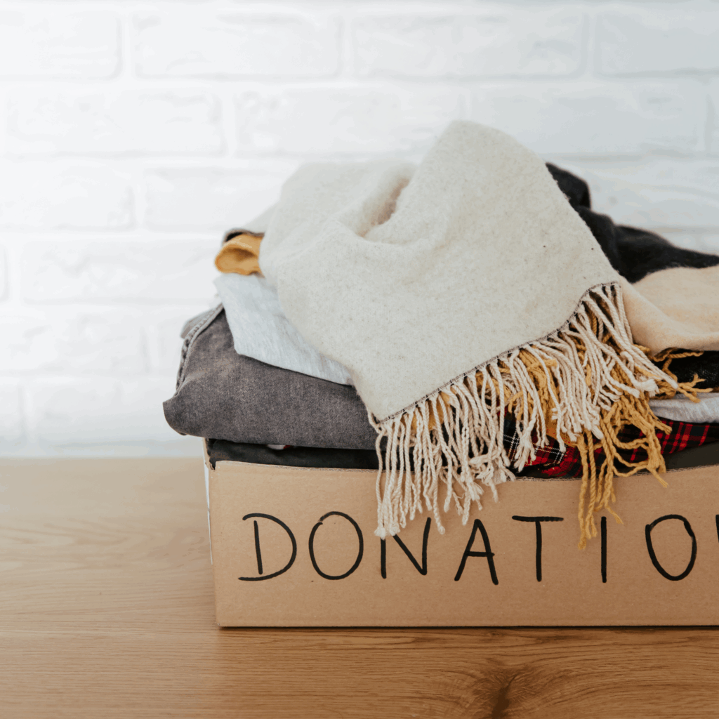 Donation box filled with neatly folded clothes and a cozy scarf, representing simple decluttering and easy ways for moms to clear space at home.